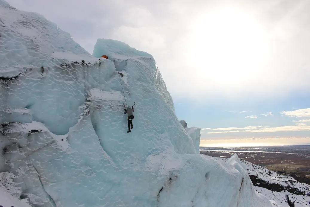 A man climbs an ice face high up in the hills